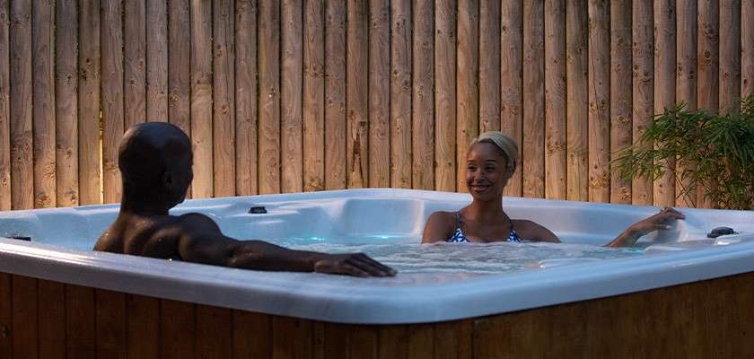 A couple in a hot tub outside their lodge 