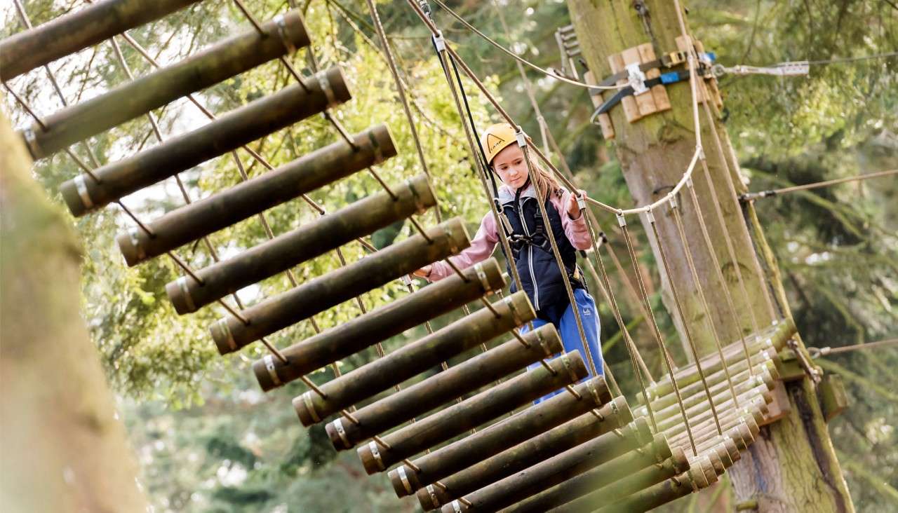 Young girl crossing a wooden bridge in the trees.