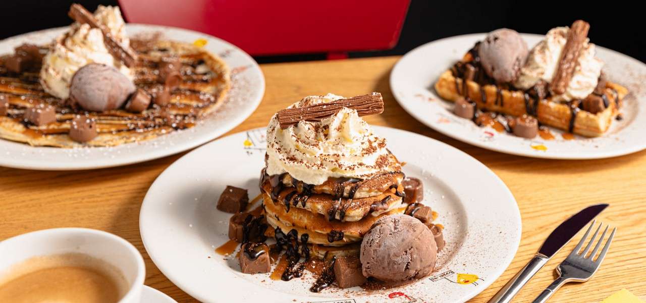 Stacked pancake topped with ice cream and chocolate sauce.