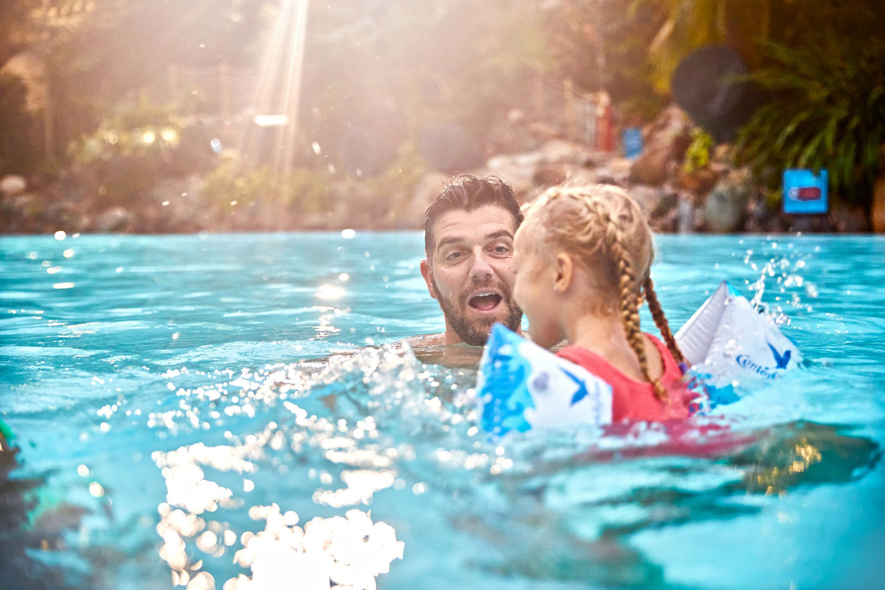 A family splashing in the indoor pool in The Subtropical Swimming Paradise.